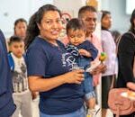 A woman holding a baby in her arms at a food fair